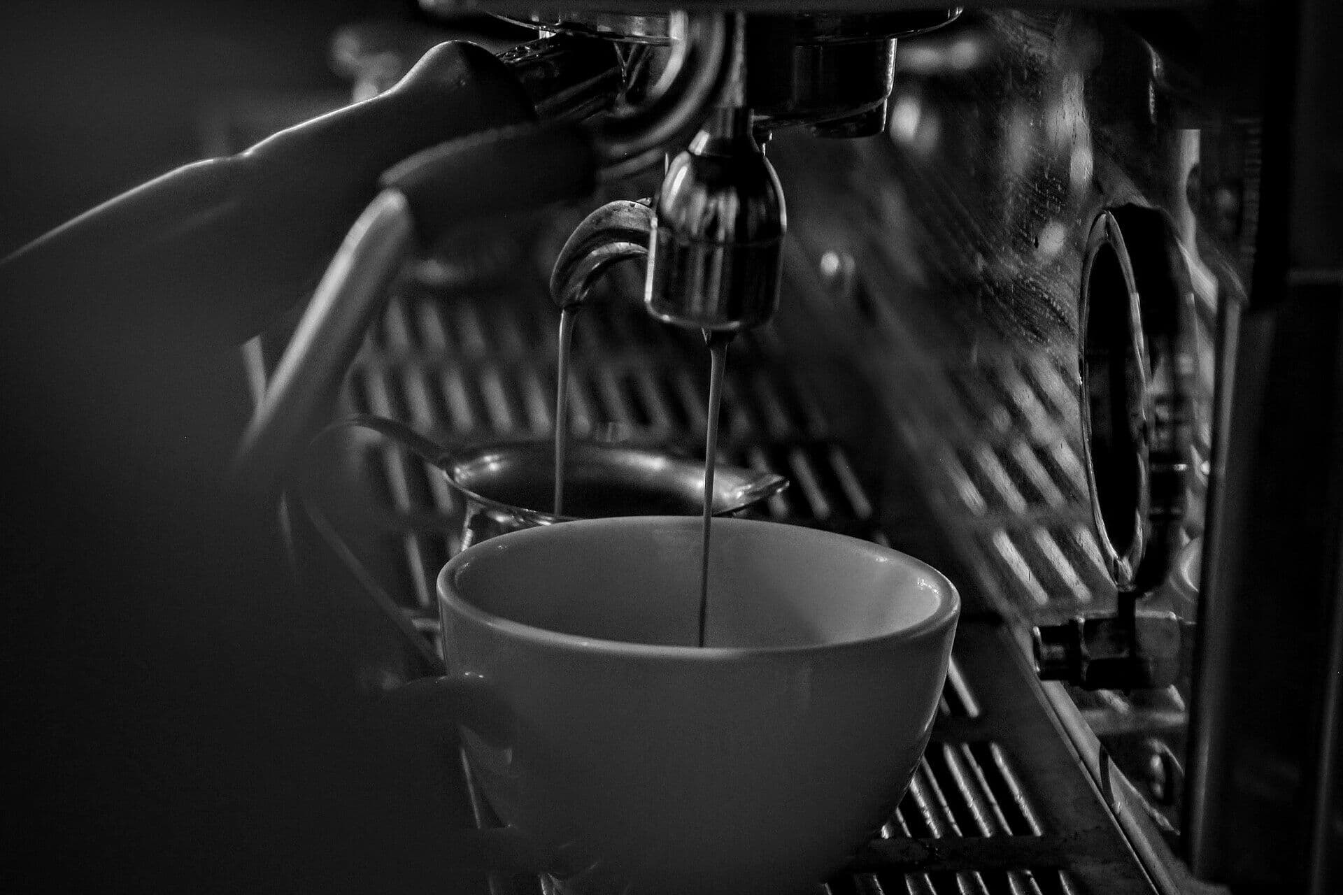 Espresso läuft aus einer Siebträgermaschine in eine Tasse, schwarzweiß